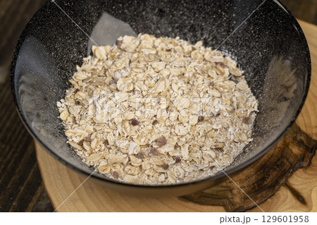 black bowl of oatmeal porridge with dried berries and fruits, filled with instant oatmeal porridge with additives black bowl of oatmeal porridge with dried berries and fruits, filled with instant oatmeal porridge with additives 129601958