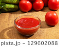 Bowl of ketchup or tomato sauce and fresh tomatoes on wood table 129602088