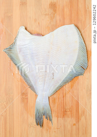 Thawed headless flounder on a wooden cutting board. Thawed headless flounder on a wooden cutting board. 129602242