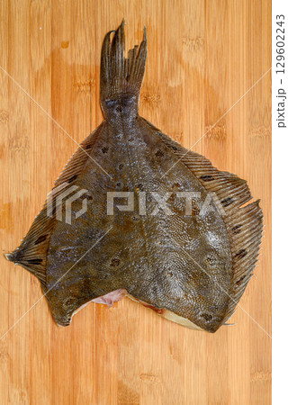 Defrosted flounder on a wooden cutting board. Defrosted flounder on a wooden cutting board. 129602243