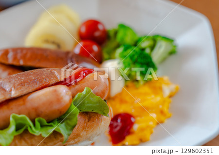 ホットドッグとスクランブルエッグ、野菜が並ぶ洋風朝食プレート ホットドッグとスクランブルエッグ、野菜が並ぶ洋風朝食プレート 129602351