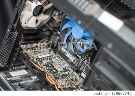 The interior of a desktop computer features a cooling fan, a graphics card, and various components in a tech-driven environment. The interior of a desktop computer features a cooling fan, a graphics card, and various components in a tech-driven environment. 129602740
