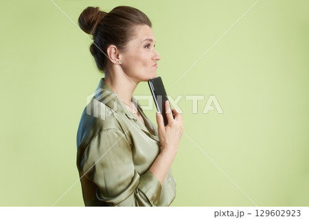 Contemplative woman with smartphone 129602923