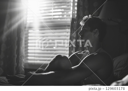 Contemplative Man Sitting by Window in Black and White Contemplative Man Sitting by Window in Black and White 129603178