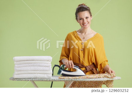 Smiling woman ironing laundry at home 129603252