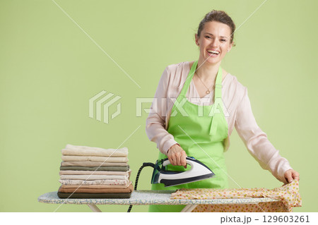 Smiling housewife ironing clothes with green backdrop Smiling housewife ironing clothes with green backdrop 129603261