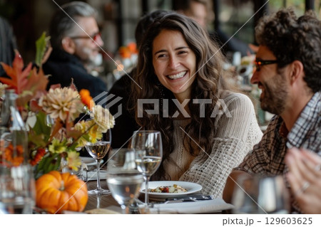 Smiling Woman Enjoying Autumn Feast Gathering with Friends at Festive Table 129603625