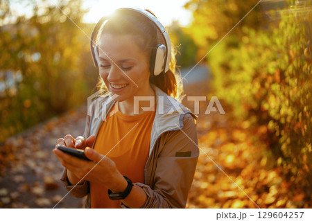 smiling stylish woman in fitness clothes in park 129604257