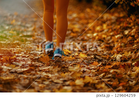 Closeup on female in fitness clothes in park walking 129604259