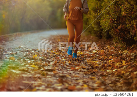 Stylish woman in fitness clothes in park running Stylish woman in fitness clothes in park running 129604261