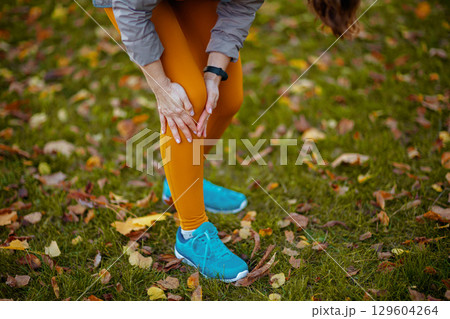 woman in fitness clothes in park having leg pain woman in fitness clothes in park having leg pain 129604264