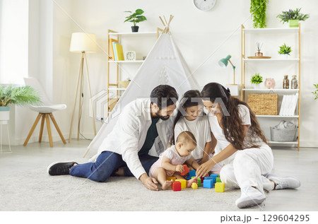 Mother, daughter and two children spending free time together, playing with colourful blocks Mother, daughter and two children spending free time together, playing with colourful blocks 129604295