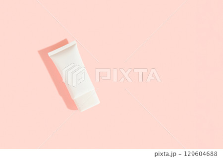 White plastic cosmetic tube on pink background. Cosmetics sale concept White plastic cosmetic tube on pink background. Cosmetics sale concept 129604688