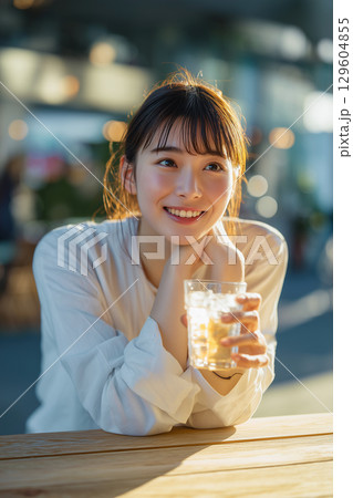 カフェタイムに笑顔こぼれる女性 ─ 柔らかな光に包まれたひととき 129604855