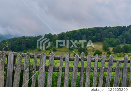 rustic wooden fence frames a lush green hillside. High quality photo 129605299