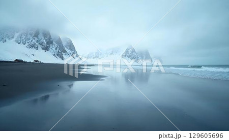 A beautiful beach with reflective water and snow-capped mountains in the background, merging coastal and alpine landscape 129605696