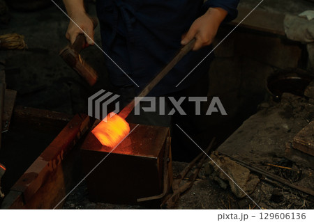 日本独自の鍛錬方法で作られる日本刀を鍛えている鍛冶屋の職人を撮影 129606136