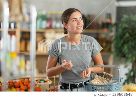 Woman in gray t-shirt in supermarket Woman in gray t-shirt in supermarket 129608649