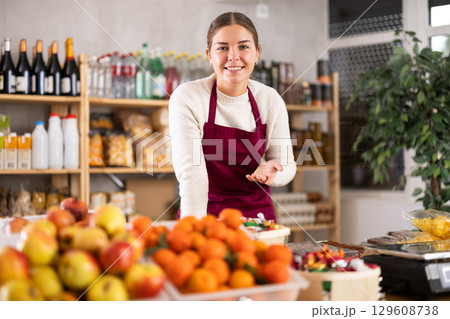 Portrait of female seller in an apron behind the counter of grocery store Portrait of female seller in an apron behind the counter of grocery store 129608738