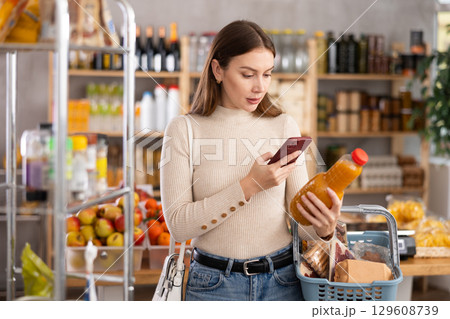 Young woman scanning qr code of peach juice Young woman scanning qr code of peach juice 129608739