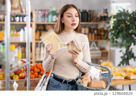 Young woman choosing cheese in grocery store 129608820