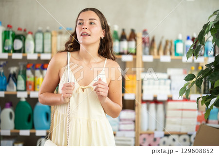 In household shop, girl customer stares at windows. 129608852
