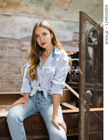 Woman posing against background of old machine tool in abandoned factory 129608869