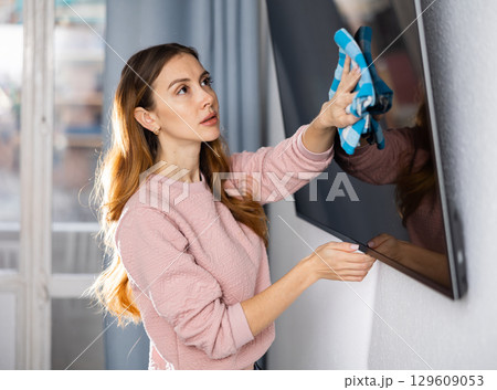 Woman is cleaning surface on the television at home Woman is cleaning surface on the television at home 129609053