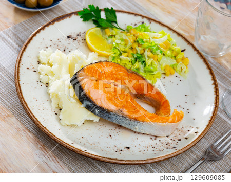 Salmon served with potatoes and salad 129609085