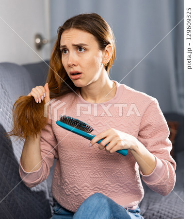 Frustrated young woman combs her hair 129609325