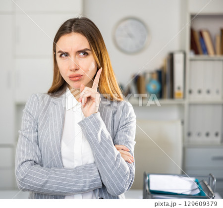 Business woman standing in office and pointing 129609379