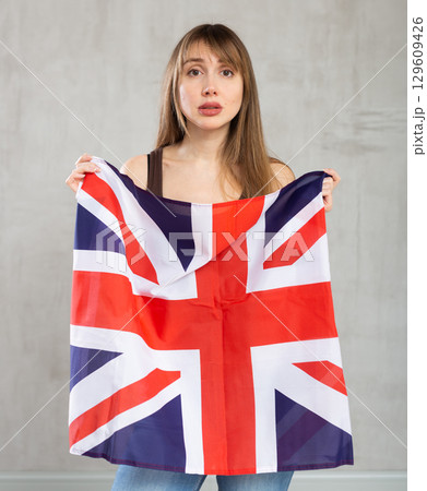 Young sad woman holding flag of Great Britain Young sad woman holding flag of Great Britain 129609426