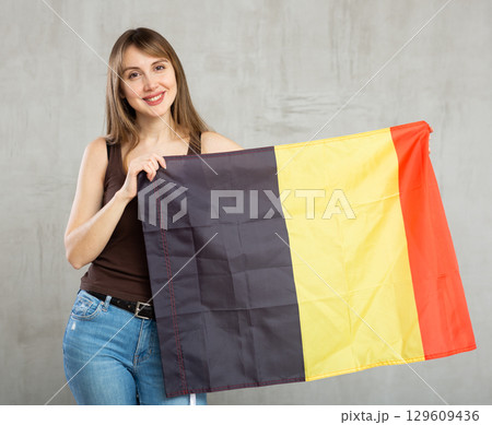 Young happy pretty woman displaying flag of belgium 129609436