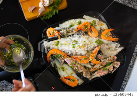Fried fish with shrimps in frying pan 129609445