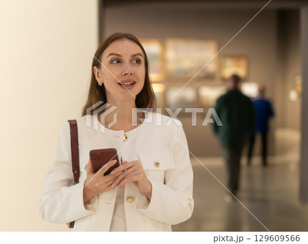 Woman with phone in museum 129609566