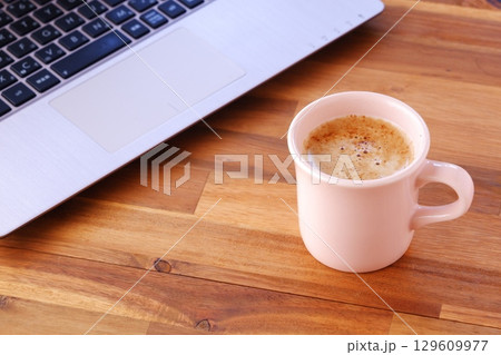 淹れたての美味しいコーヒーを飲みながら、ノートパソコンでデスクワークをしているイメージ 129609977
