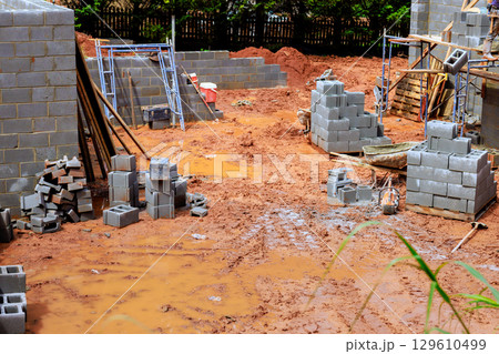 Construction site with gray concrete blocks muddy ground during cloudy day in an urban area Construction site with gray concrete blocks muddy ground during cloudy day in an urban area 129610499