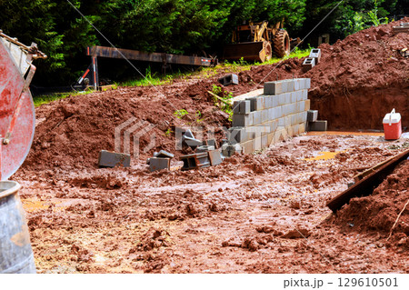 Construction site with muddy ground, building materials during works day in rural area Construction site with muddy ground, building materials during works day in rural area 129610501