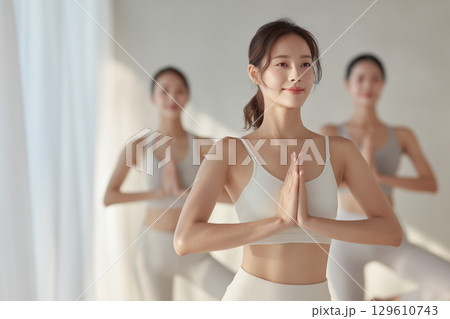 朝の光が心地よいヨガスタジオで木のポーズをとる女性 129610743
