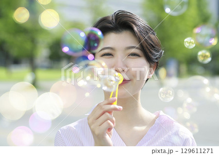 公園でシャボン玉を吹く若い女性 129611271