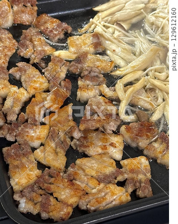 Grilled samgyeopsal, thick slices of pork belly with a perfect balance of crispy edges and tender meat. Served with lettuce, garlic, and dipping sauces for a classic Korean barbecue experience. 129612160