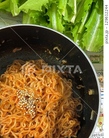 Bibimyeon, a flavorful Korean dish featuring cold noodles tossed in a spicy, tangy sauce, topped with fresh vegetables and a boiled egg. Perfect for summer meals, showcasing vibrant flavors and colors Bibimyeon, a flavorful Korean dish featuring cold noodles tossed in a spicy, tangy sauce, topped with fresh vegetables and a boiled egg. Perfect for summer meals, showcasing vibrant flavors and colors 129612244