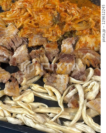 Juicy grilled samgyeopsal paired with savory mushrooms and tangy, sizzling kimchi, creating a perfect balance of rich, earthy, and spicy flavors in every delicious, mouthwatering bite. 129612245