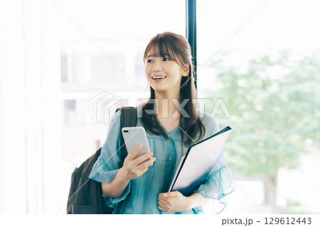 スマホを見る女子大生 129612443