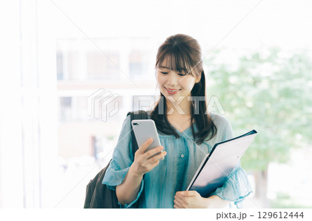 スマホを見る女子大生 129612444