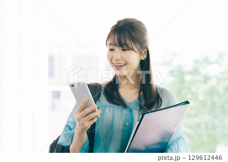 スマホを見る女子大生 129612446