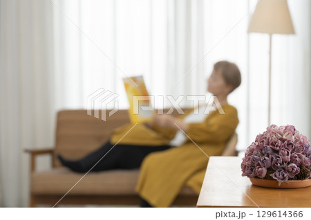リビングのソファーで本を読むシニア女性 129614366