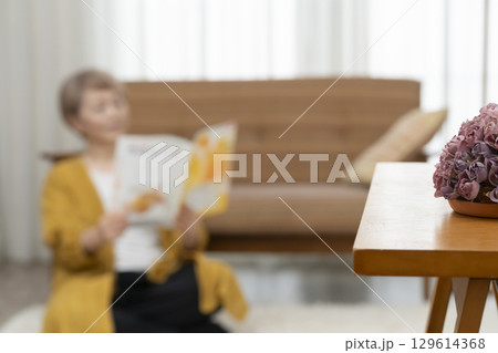 リビングのソファーで本を読むシニア女性 129614368