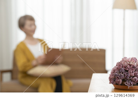リビングのソファーで本を読むシニア女性 129614369