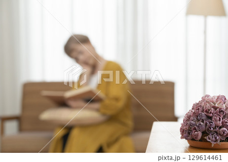 リビングのソファーで趣味のウクレレを弾くシニア女性 129614461